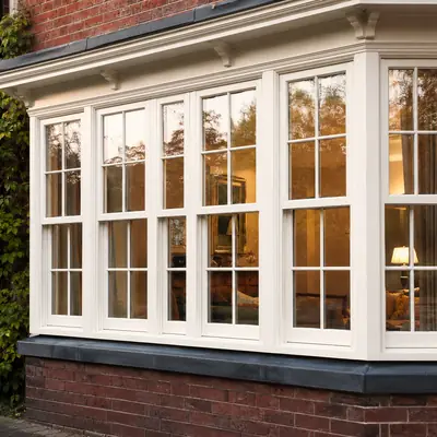 White timber sliding sash bay window with stone cill on a red brick period house